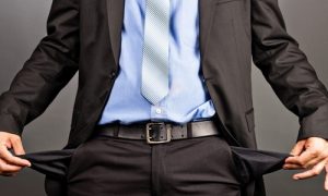 Business man showing his empty pockets  on gray background